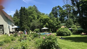 Un jardin bien entretenu, doté d’une piscine, d’un espace salon extérieur et d’un banc rouge.