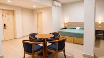 A hotel room with a bed, a round table with chairs, and a wooden floor.