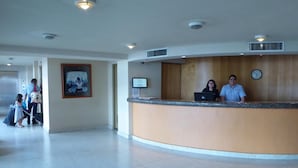 A hotel reception area with a curved counter, a clock, and a framed picture on the wall.