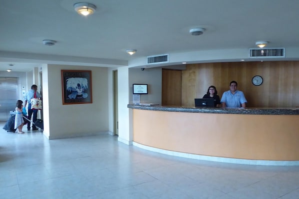 A hotel reception area with a curved counter, a clock, and a framed picture on the wall.