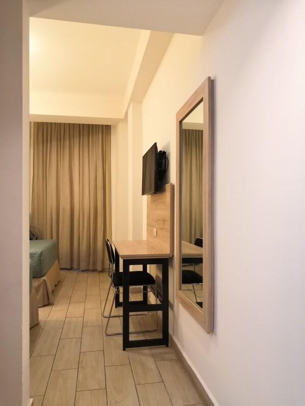 A compact hotel room with a wooden dining table, a TV mounted on the wall, a bed with a green cover, and a large mirror. - Hotel Son-Mar Monterrey Centro (Monterrey)