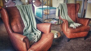 A hotel room with a bed, two leather armchairs, a small table with a lamp, and a wardrobe. - No. 21 York (York)