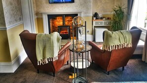 A living room with two leather armchairs, a television, a fireplace, and a small table with a lamp. - No. 21 York (York)