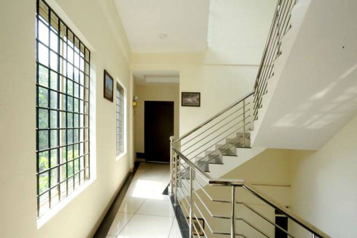 A corridor with a staircase, a door at the end, and a window with bars.