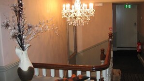 Eine Treppe mit einem Chandelier, einer Blumenvase und einem Tablett mit Orangen.