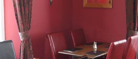 A restaurant with red walls, leather booths, and wooden tables.