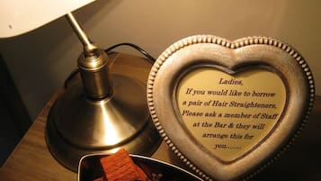 A heart-shaped plaque with text offering hair straighteners for ladies, a lamp, and a tray with a red object.