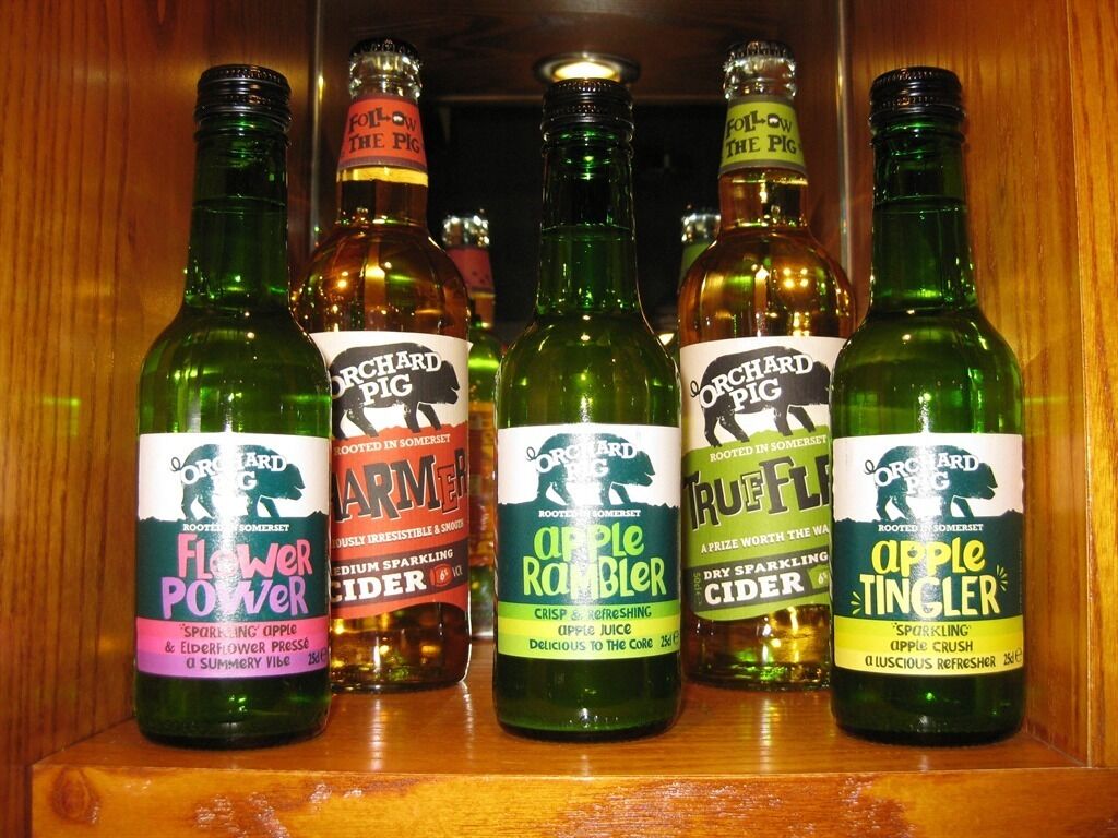 Verschiedene Flaschen Orchard Pig Apfelwein auf einem Holzregal.