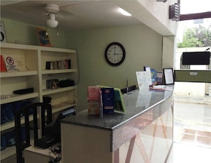 A reception desk with a clock, a bulletin board, and a counter with brochures.