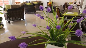 A living room with a white sofa, a dark-colored sofa, a coffee table with a potted plant, and a painting on the wall. - Hotel Isleño (Isla Mujeres)