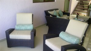 Two wicker armchairs with cushions, a small table with a vase, and a staircase in the background. - Hotel Isleño (Isla Mujeres)
