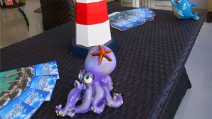 A table with a decorative lighthouse, a purple octopus figurine, and a blue teapot. - Hotel Isleño (Isla Mujeres)