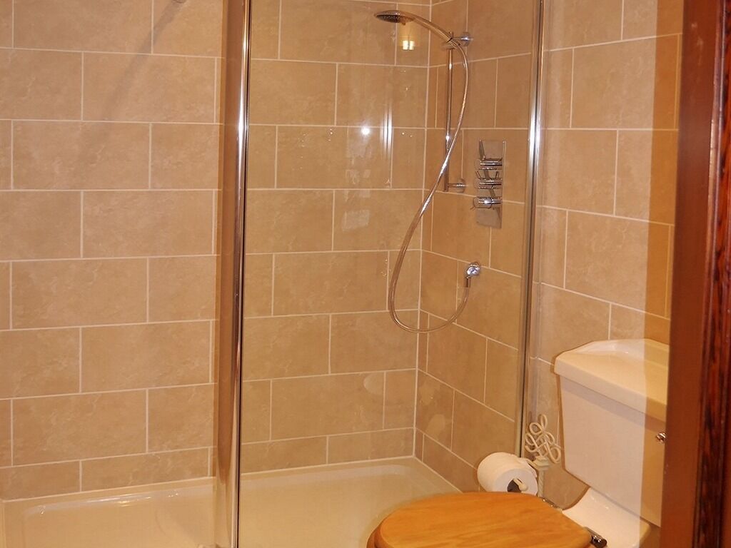 A bathroom with a glass-enclosed shower, a toilet, and a sink.
