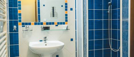 A bathroom with blue and white tiles, a sink, a mirror, and a shower enclosure.