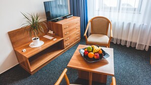 Een hotelkamer met een houten bureau, een televisie, een stoel en een schaal fruit.