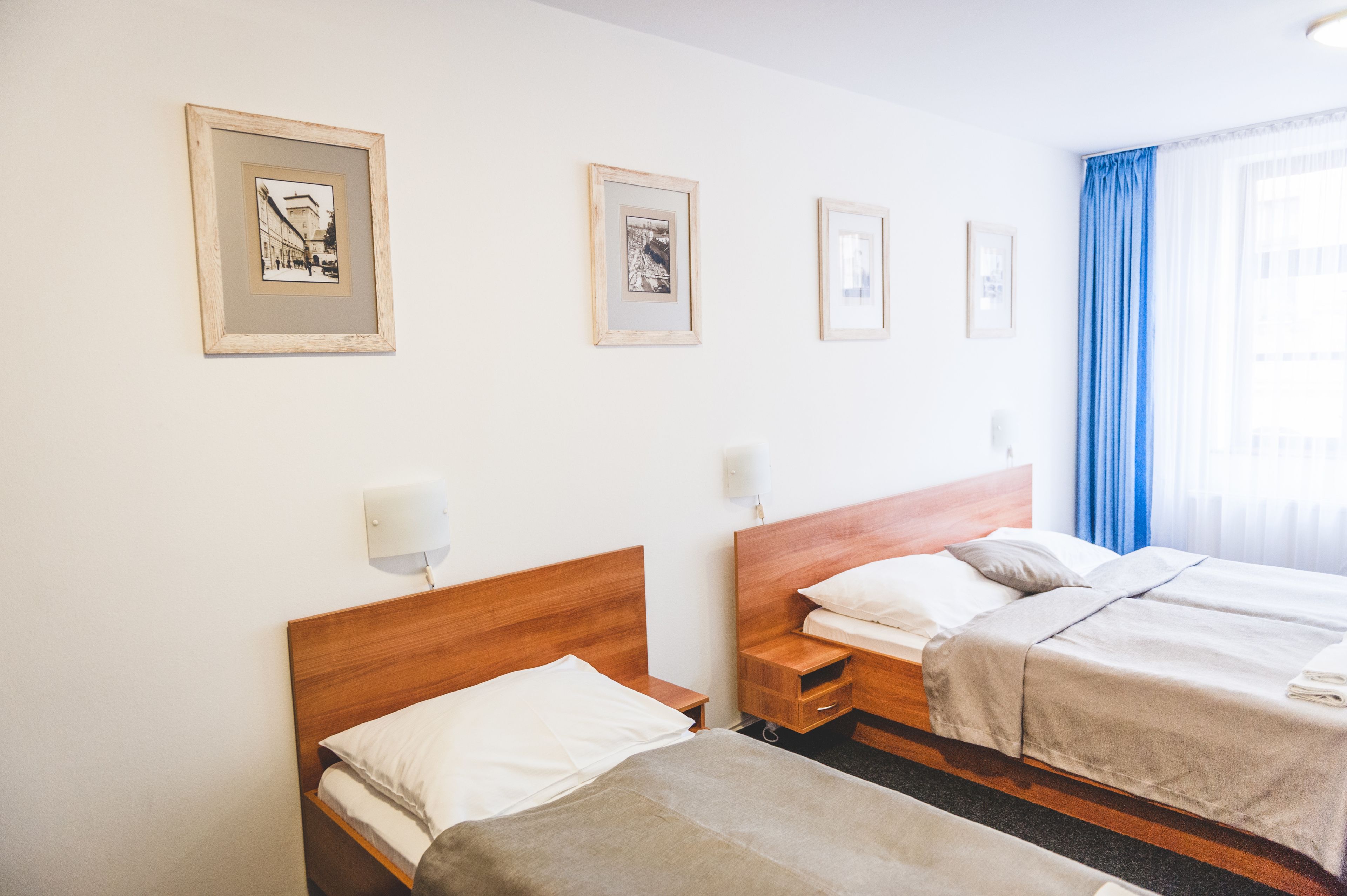 Ein Hotelzimmer mit zwei Betten, einem Holz-Kopfteil, einem Nachttisch und gerahmten Bildern an der Wand.