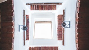 Een trap met uitzicht op een kamer, met een raam, bakstenen muren en een wit plafond.