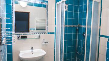Een badkamer met een witte wastafel, een spiegel en een douche met blauwe tegels.
