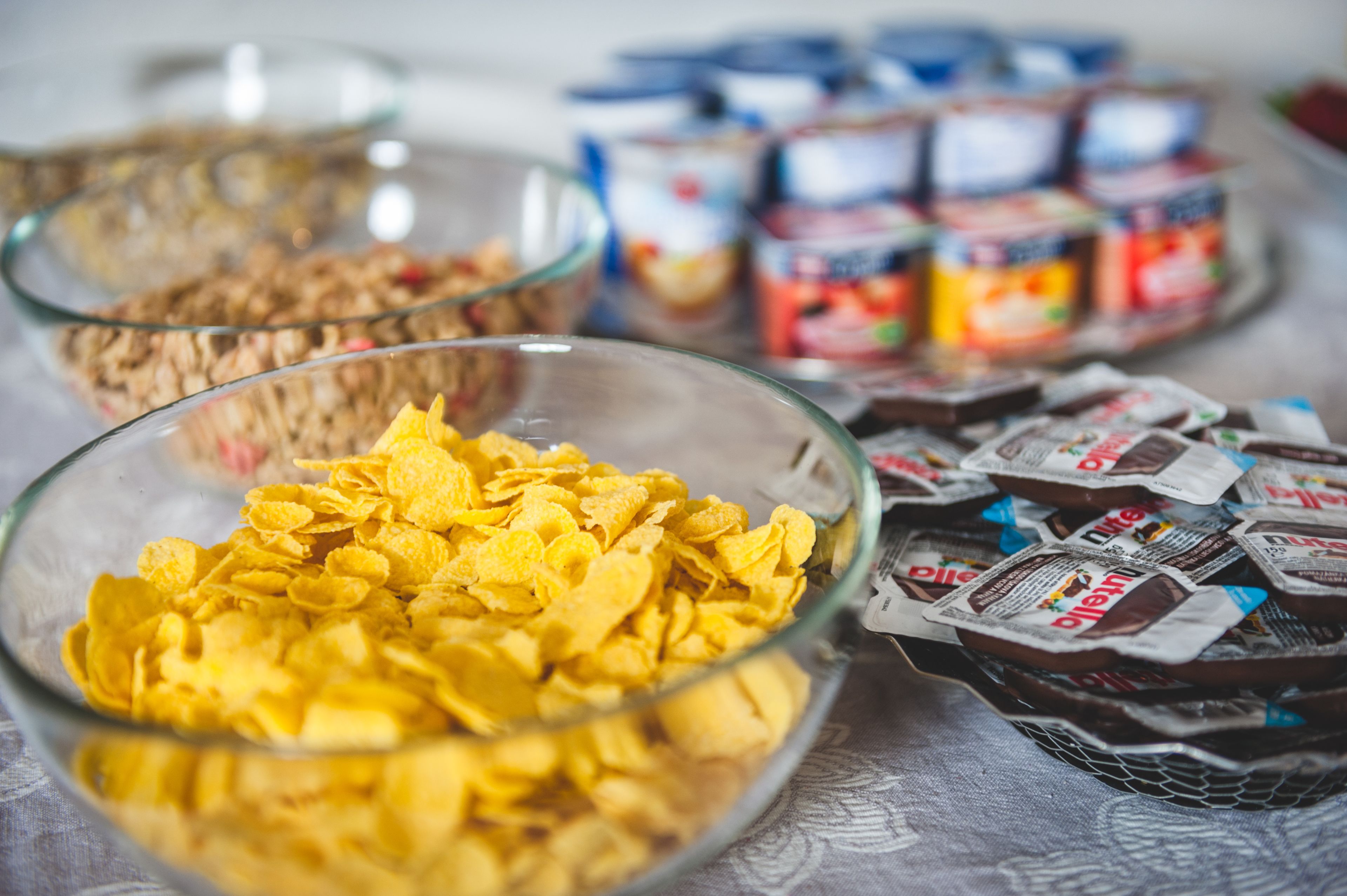 Uma mesa com tigelas de cereais e potes de geleias.