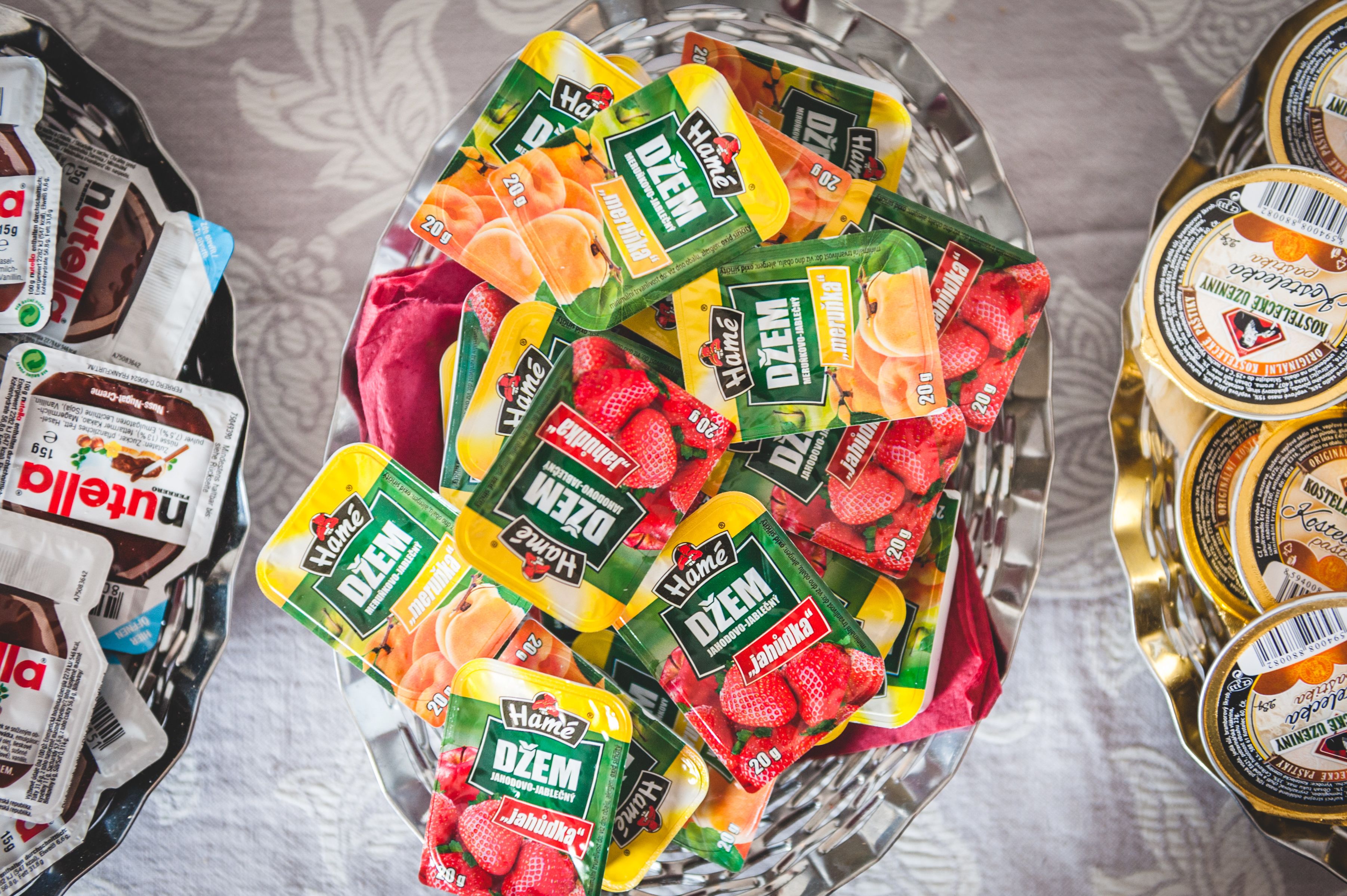 Een glazen schaal gevuld met verschillende verpakte levensmiddelen, waaronder fruit en zuivere melkproducten.