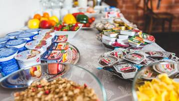 A buffet table with various food items including yogurt, packaged snacks, and fruits.