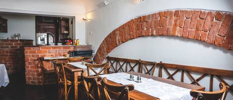 A restaurant with brick walls, wooden tables, and chairs.