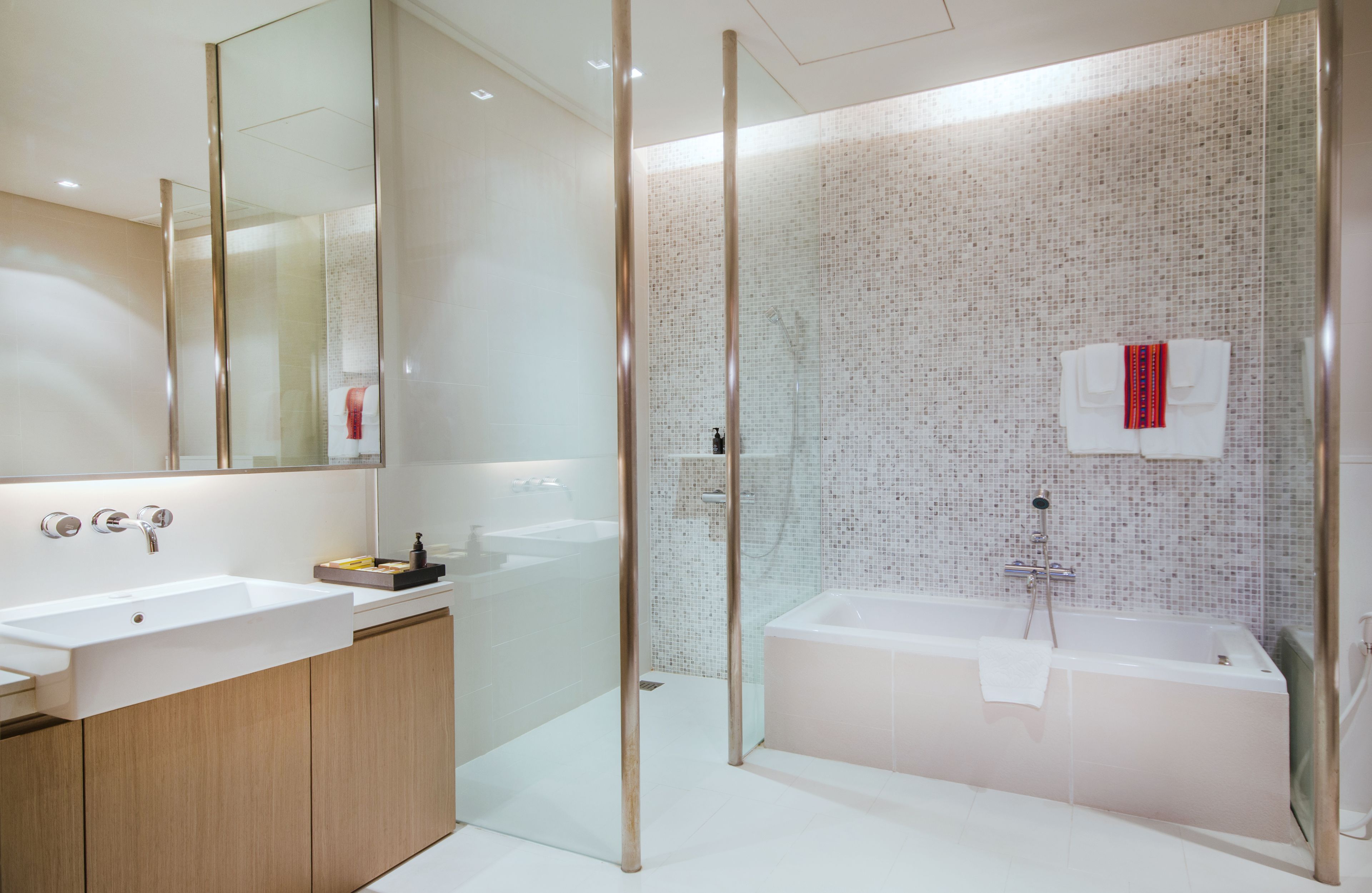 A modern bathroom with a glass shower enclosure, a freestanding bathtub, and a large mirror.