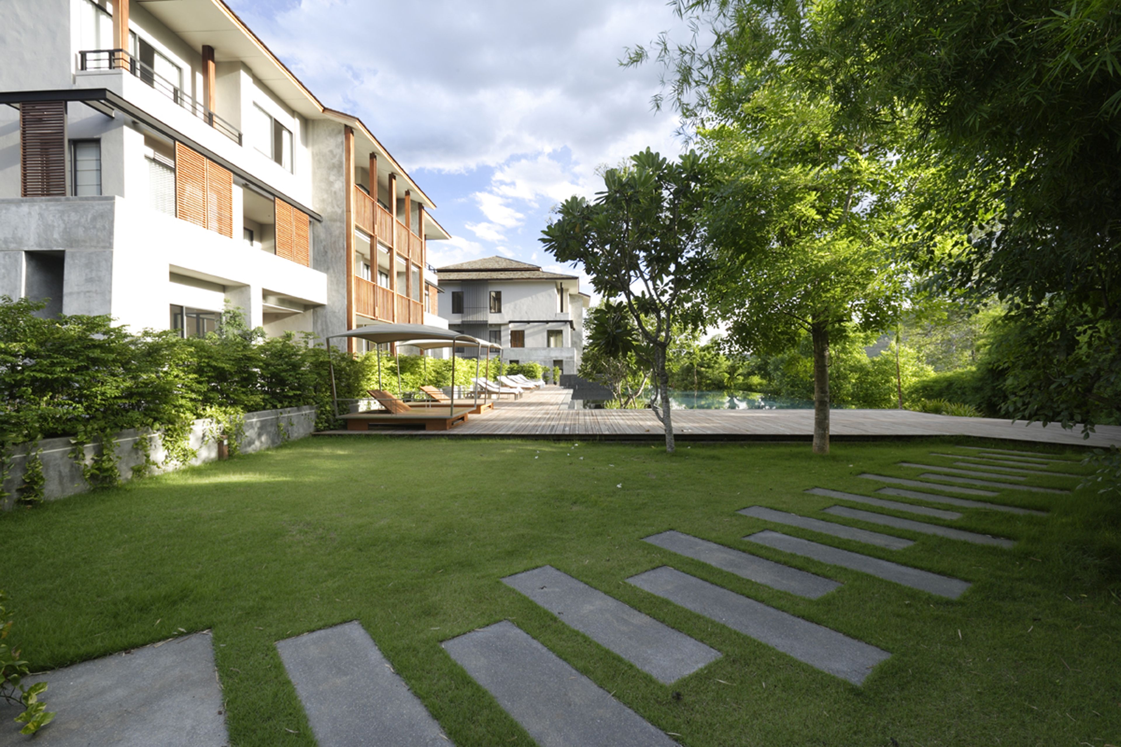 Un immeuble résidentiel moderne doté d’une pelouse bien entretenue, d’une piscine et offrant une vue sur un ciel dégagé.