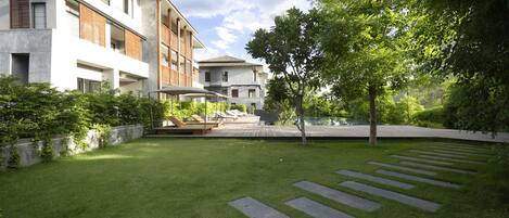 Un immeuble résidentiel moderne doté d’une pelouse bien entretenue, d’une piscine et offrant une vue sur un ciel dégagé.