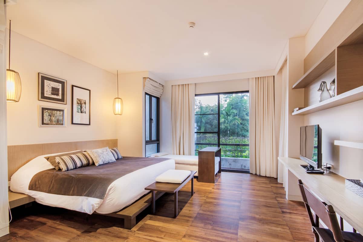 A modern hotel room with a large bed, a desk, and a TV.