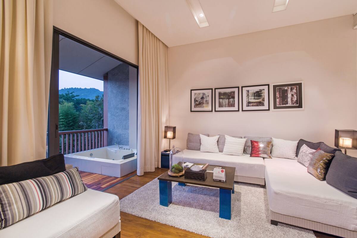 A modern living room with a large window, a sofa, a coffee table, and a view of the outdoors.