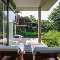 Relax in a serene outdoor lounge area with a tranquil view of the lush garden and pool.