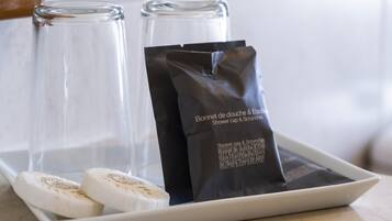 Una bandeja con dos jabones blancos y una bolsa negra que dice "Bonheur de douche & Essentiel Shower cap & Scrunchie".