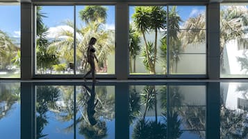 Una piscina techada, una piscina al aire libre, sombrillas