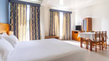 A hotel room with a large bed, a desk with a chair, a television, and a cabinet.