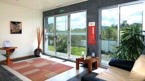 A modern hotel lobby with a large window offering a view of greenery and hills.