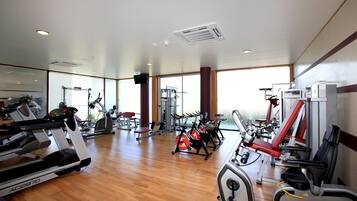 Un'ampia palestra con diverse attrezzature per esercizi, grandi finestre e un pavimento in legno.