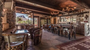 A rustic interior with stone walls, wooden furniture, and a bar area with shelves of bottles. - White Stallion Ranch (Tucson)