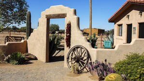 A rustic building with a large wooden wheel, a cactus, and a wooden gate. - White Stallion Ranch (Tucson)