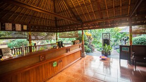 A reception area with a wooden reception desk, a tiled floor, and a thatched roof. - Zen Resort Bali (Buleleng)