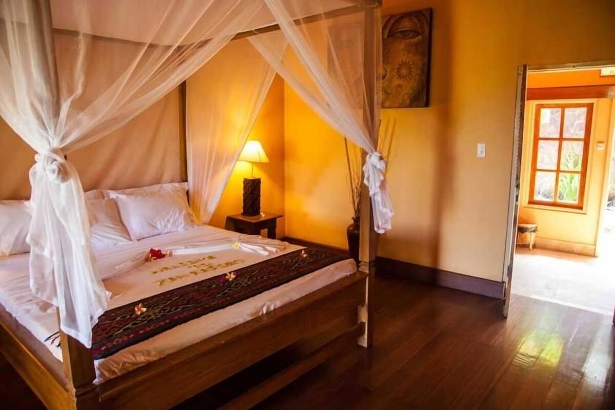 A room with a bed, a nightstand, a lamp, and a painting on the wall.