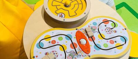 Un tapis de jeu avec un labyrinthe, une petite voiture et un ours en peluche.