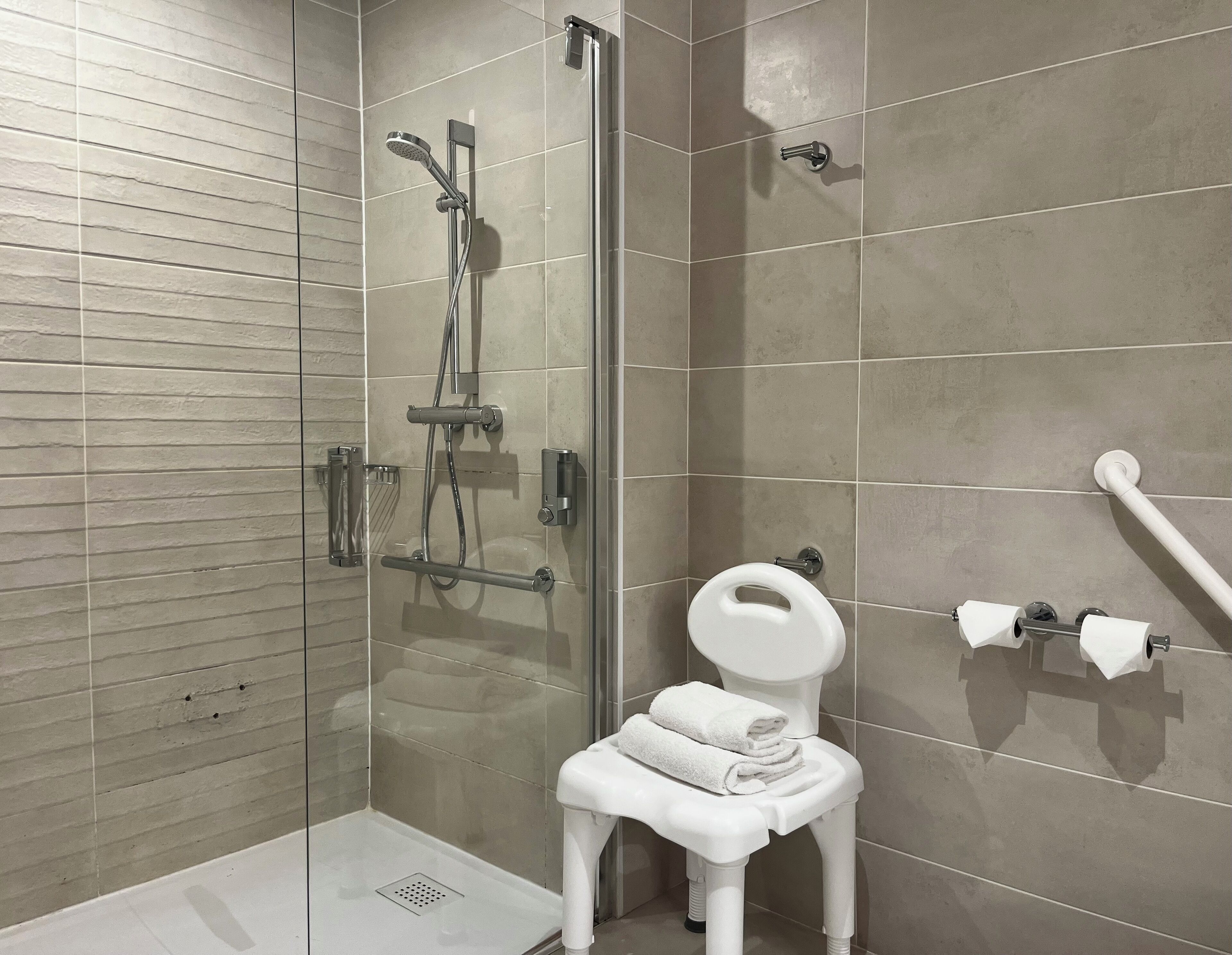 A modern bathroom with a glass-enclosed shower, a white toilet, and a towel rack.