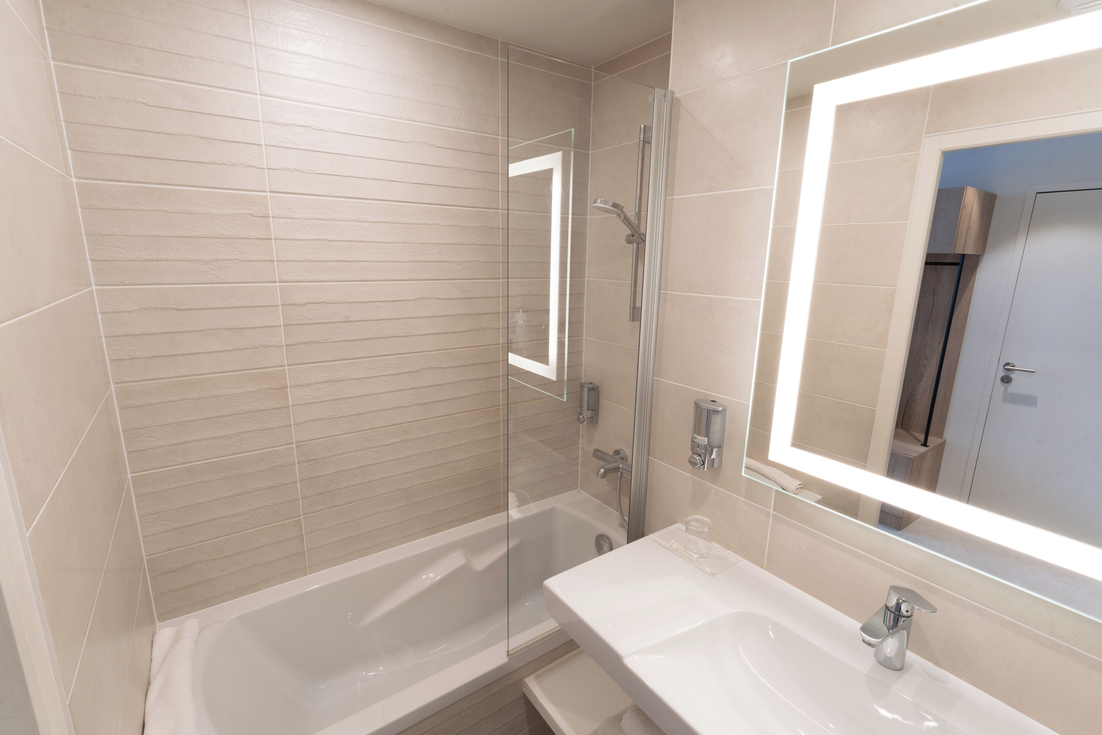 A modern bathroom with a glass-enclosed shower, a white sink, and a large mirror.