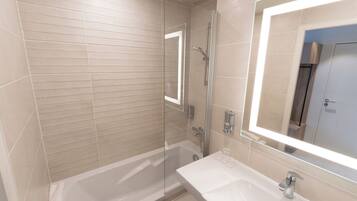 A modern bathroom with a glass-enclosed shower, a white sink, and a large mirror.