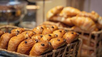 A display of assorted pastries, including croissants and chocolate-filled pastries, arranged in baskets.