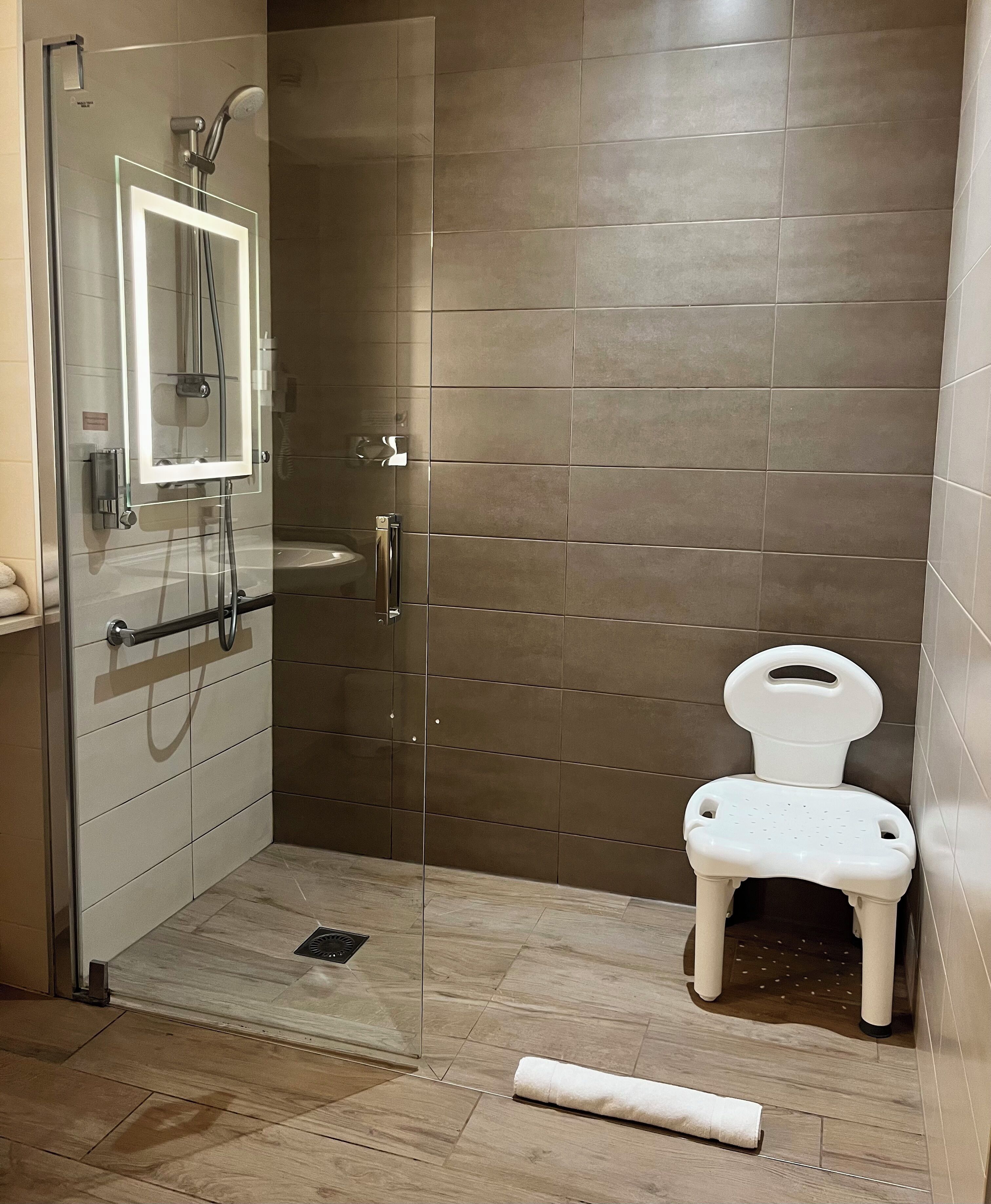 A modern bathroom with a glass-enclosed shower, a white toilet, and a small sink.