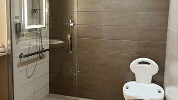 A modern bathroom with a glass-enclosed shower, a white toilet, and a small sink.