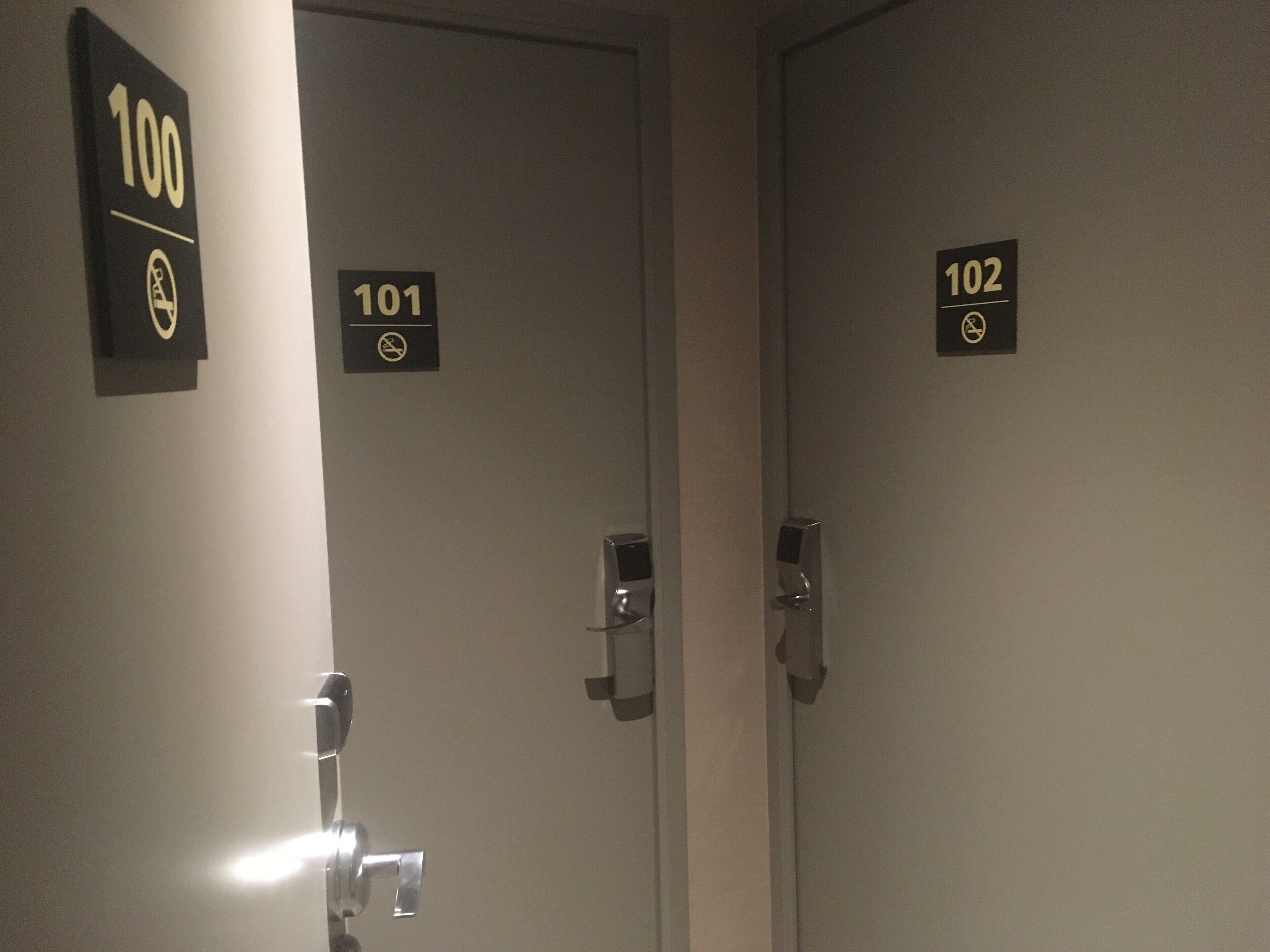 Tres puertas con los rótulos 100, 101 y 102 en un pasillo.