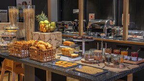 Un buffet proposant une variété de plats, notamment des pâtisseries, des fruits et des boissons.